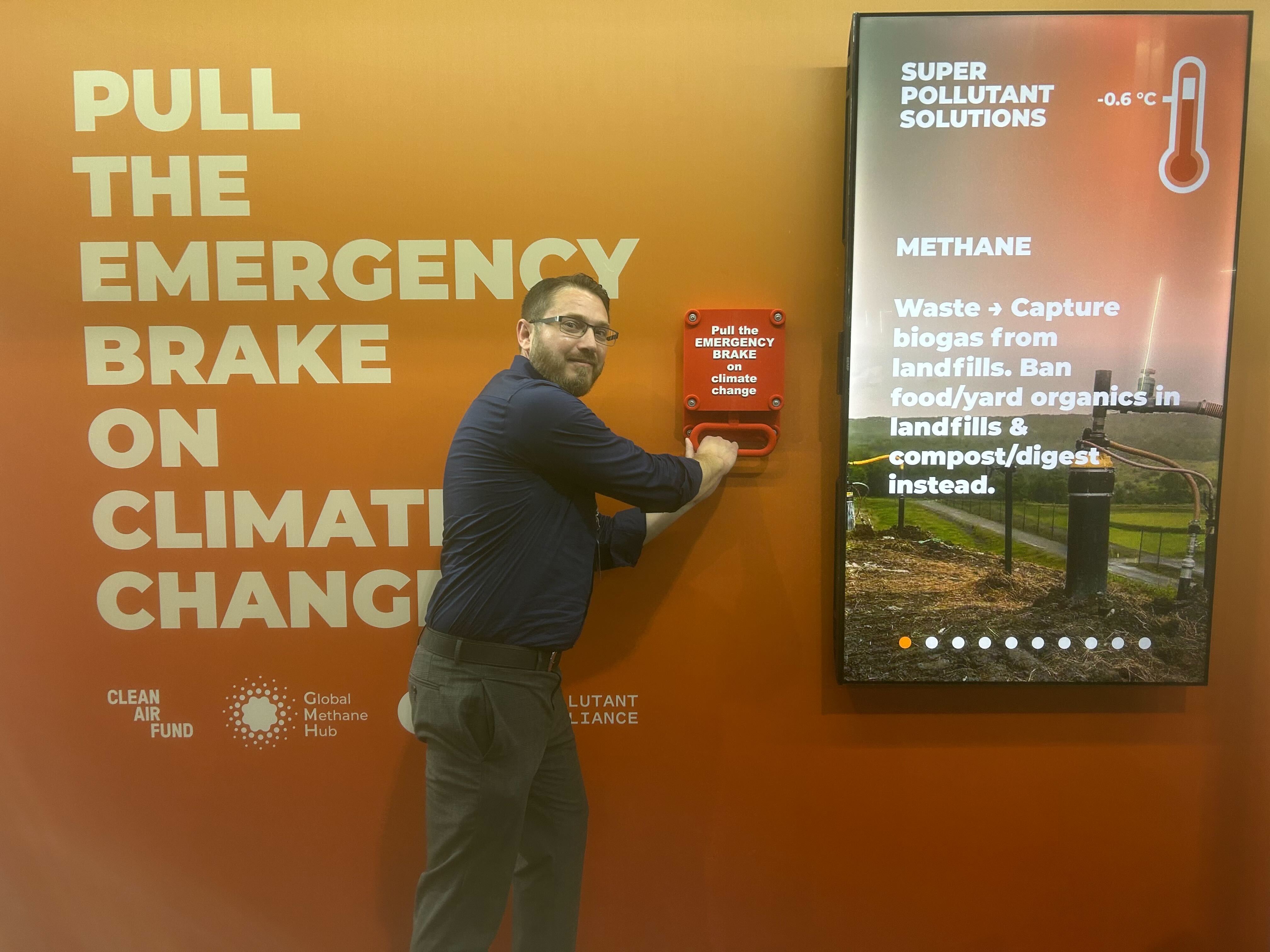 An image of Project Drawdown senior policy advisor Dan Jasper pulling a red emergency brake at an exhibit on methane at COP30