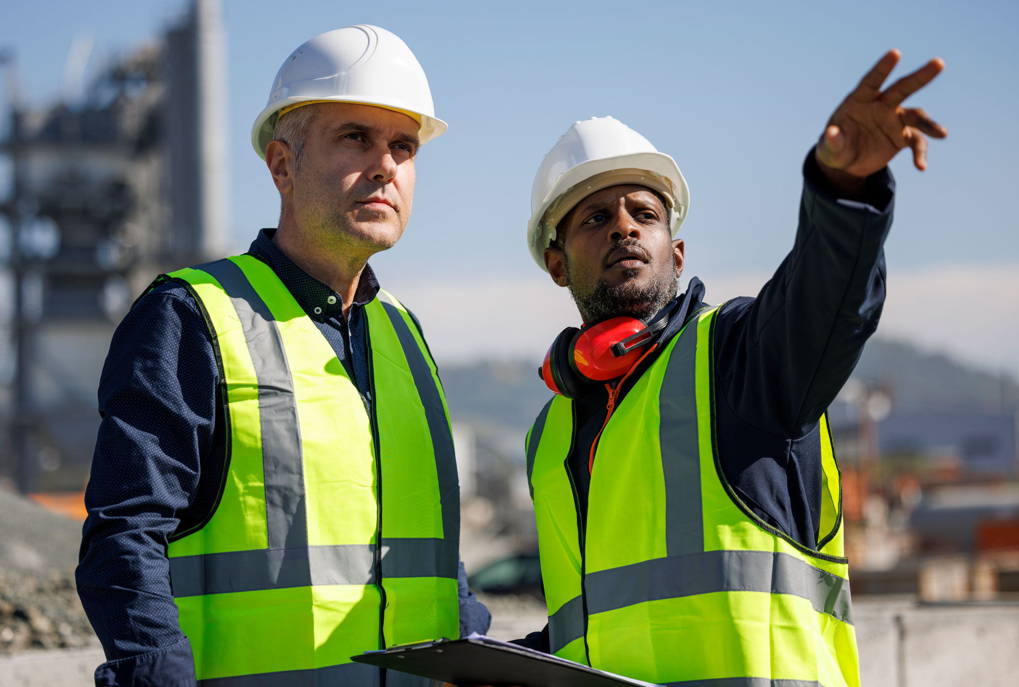 Two engineers discussing maintenance plans at outdoor plant.
