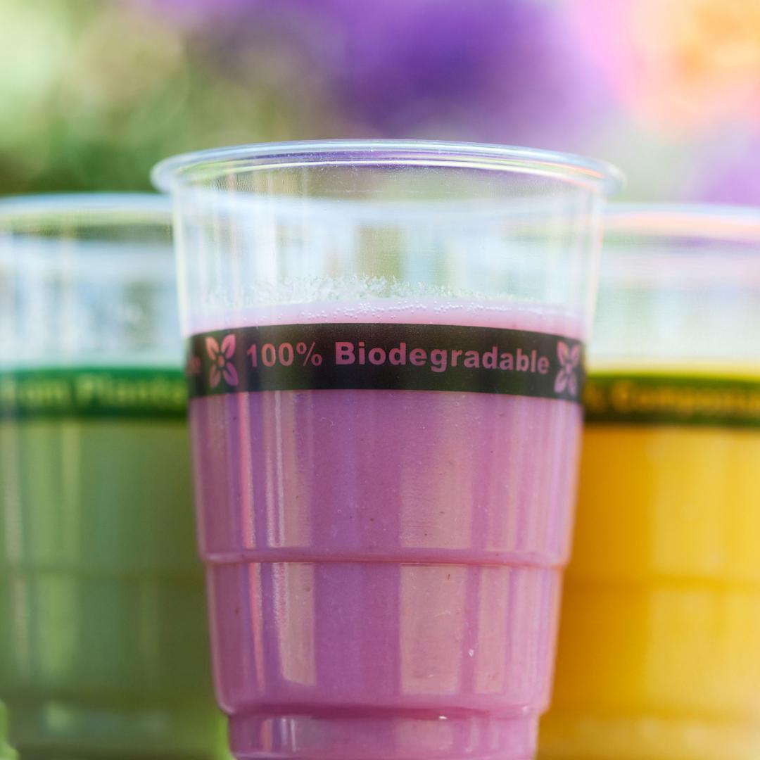 Colorful smoothies in plastic cups with label 100% biodegradable