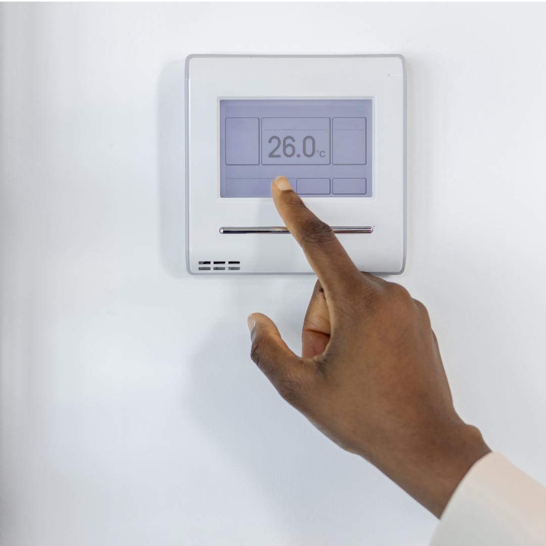Hand pointing to smart thermostat on the wall