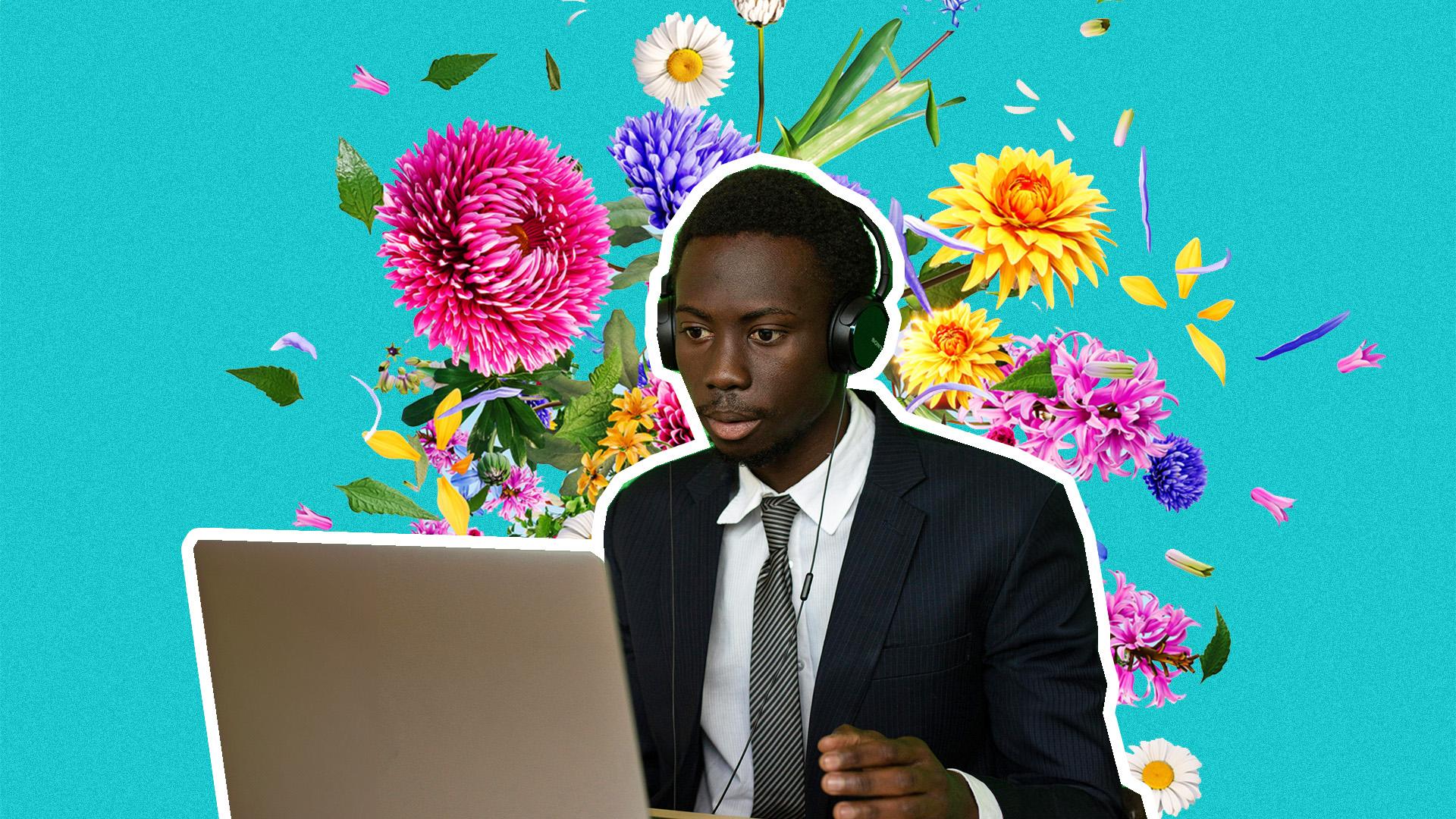 A man at his computer wearing a suit with flowers in the background