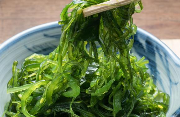 An image of chopsticks picking up seaweed from a small bowl