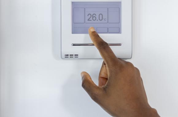 Hand pointing to smart thermostat on the wall