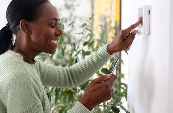 Woman setting smart thermostat